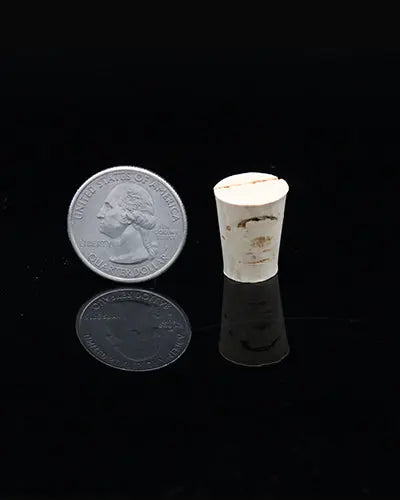Close-up of a small, natural cork toy part, measuring 3/4" in length and 1/2" in height, with a textured, earthy surface.