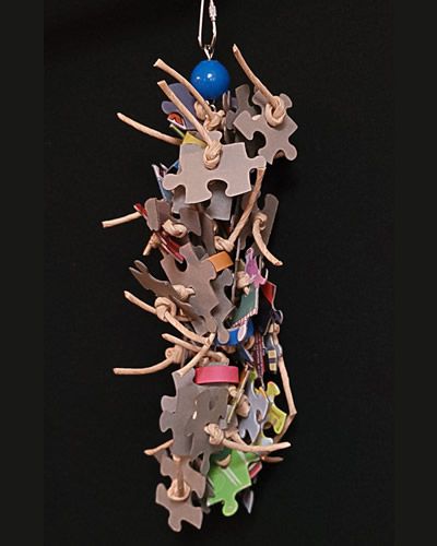 Colorful bird toy with cardboard puzzle pieces, bagels, and twisted paper rope hanging from a sturdy chain for playful birds.