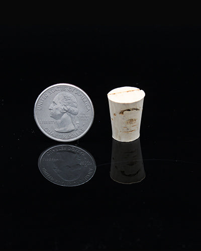 Close-up of a small, natural cork toy part, measuring 3/4" in length and 1/2" in height, with a textured, earthy surface.